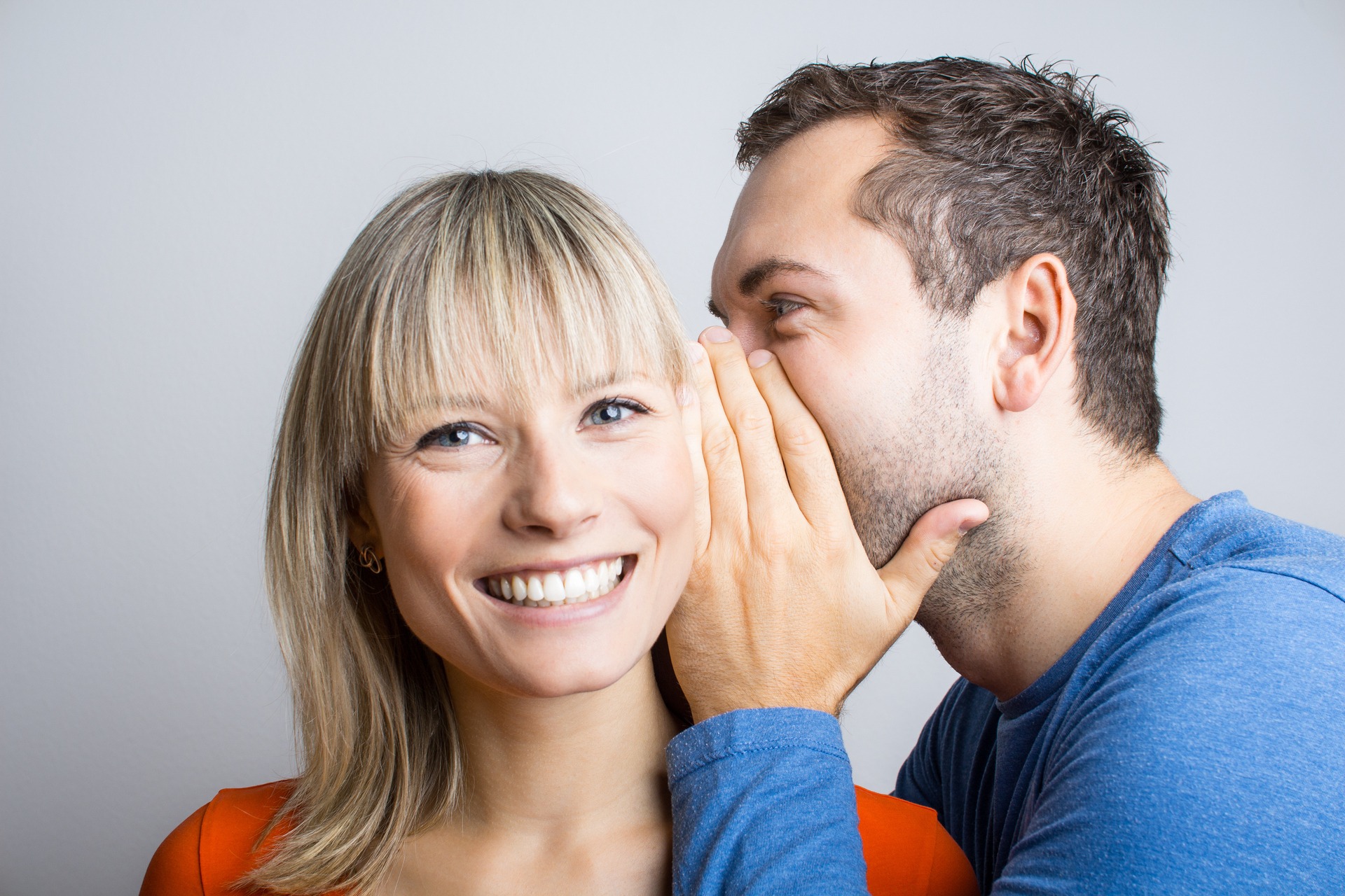 Mann-fluestert-Frau-was-ins-Ohr